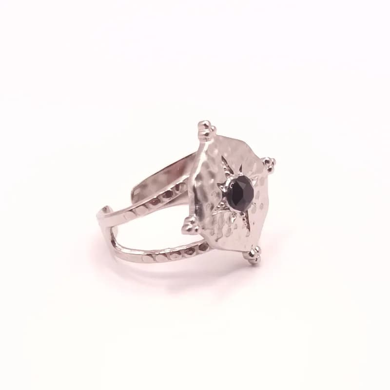 Bague argentée martelée vue de trois quarts, avec une étoile et une pierre noire au centre.