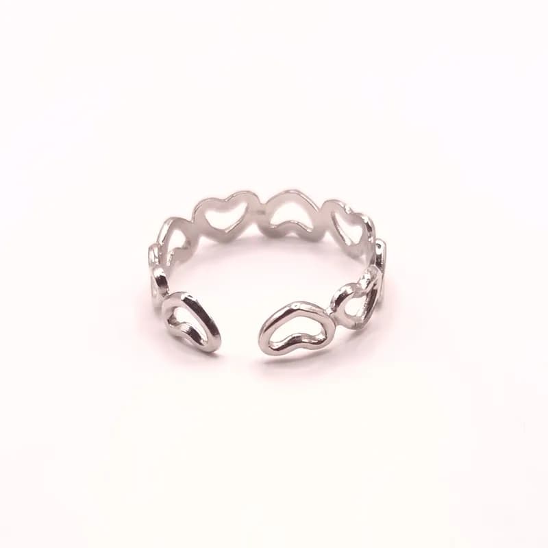 Bague ouverte argentée formée de cœurs ajourés, vue de face sur fond blanc.
