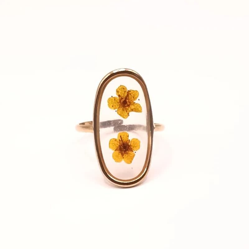 Bague dorée à fleurs séchées jaunes dans résine transparente - vue de face