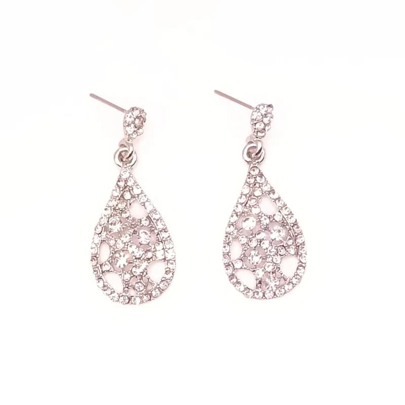 Paire de boucles d'oreilles pendantes en goutte ajourée argentée sertie de pierres scintillantes, vue de face.